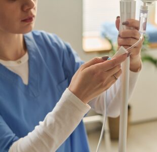 Close,Up,Of,Young,Adult,Caucasian,Nurse,Adjusting,Intravenous,Drip